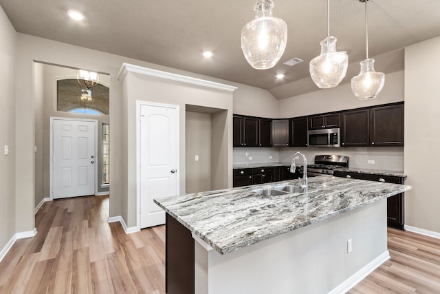 kitchen with hanging light fixtures, decorative backsplash, a kitchen island with sink, appliances with stainless steel finishes, and sink