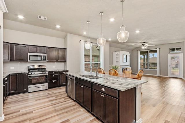 kitchen with a center island with sink, appliances with stainless steel finishes, ceiling fan, sink, and dark brown cabinets