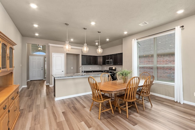 dining room featuring light wood-type flooring, a textured ceiling, and sink