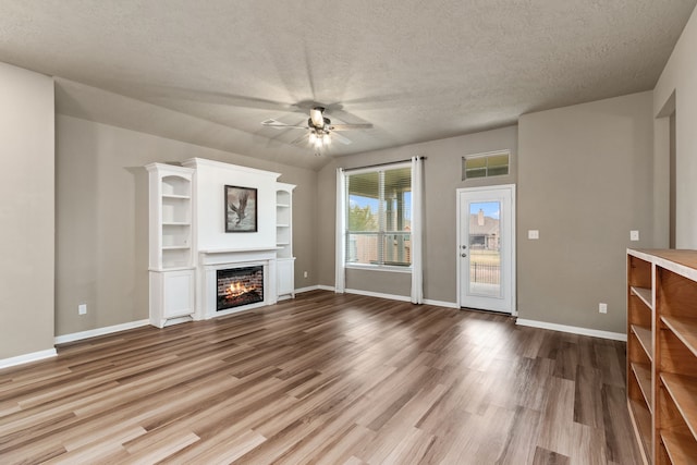 unfurnished living room featuring a textured ceiling, ceiling fan, and light hardwood / wood-style floors