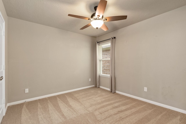 spare room featuring a textured ceiling, light carpet, and ceiling fan