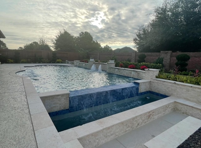 pool at dusk featuring pool water feature