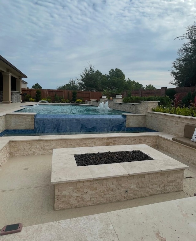 view of pool with a patio, pool water feature, and an outdoor fire pit