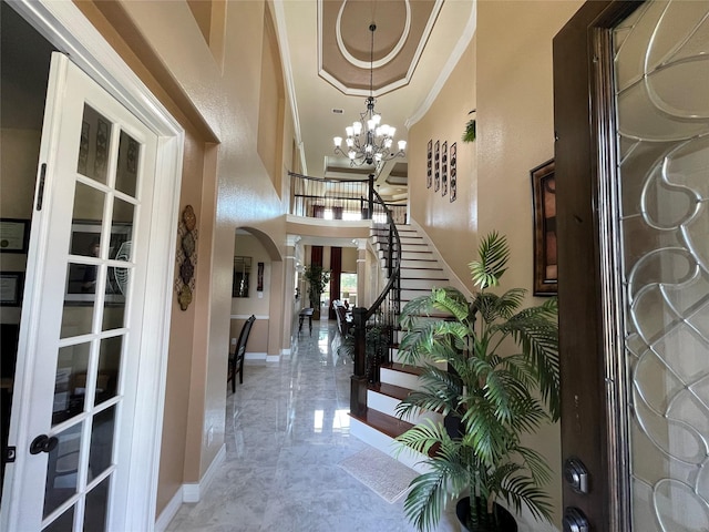 entryway featuring a high ceiling, ornamental molding, and an inviting chandelier