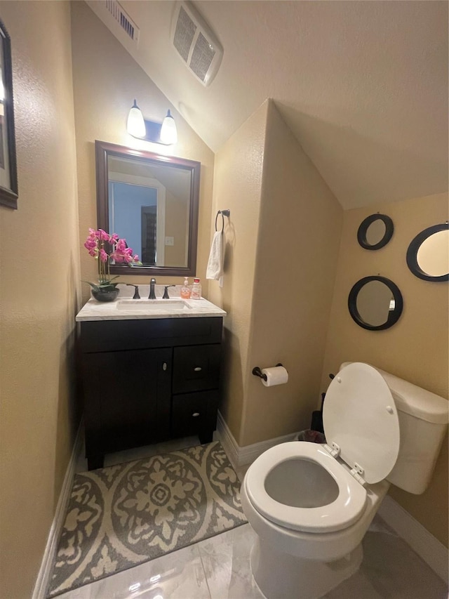 bathroom with vanity, toilet, and vaulted ceiling