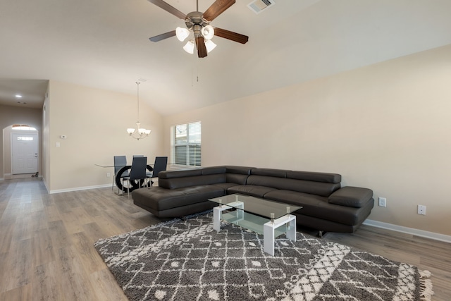 living room featuring lofted ceiling, ceiling fan with notable chandelier, and hardwood / wood-style floors