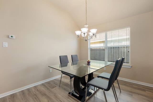 dining area featuring light hardwood / wood-style floors, an inviting chandelier, and vaulted ceiling