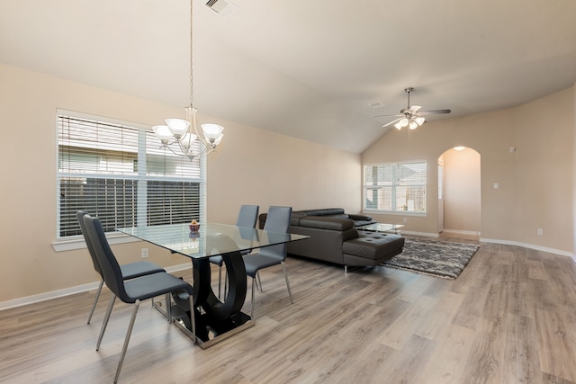 dining area featuring ceiling fan with notable chandelier, lofted ceiling, and light wood-type flooring