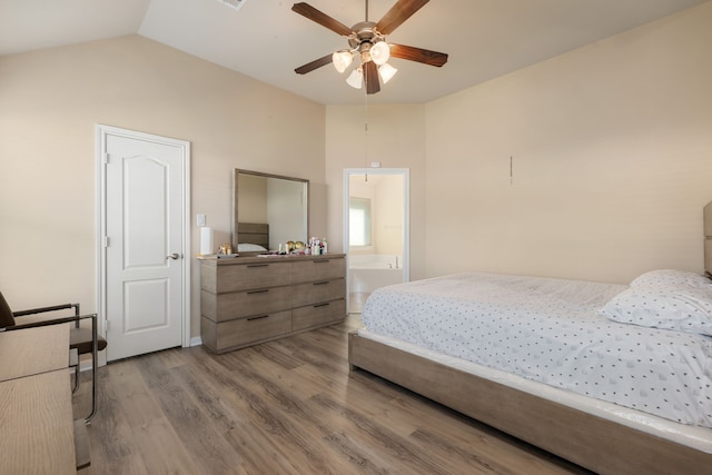 bedroom featuring ceiling fan, light hardwood / wood-style flooring, connected bathroom, and vaulted ceiling