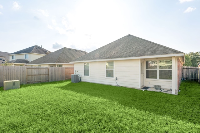 back of property featuring central AC and a yard