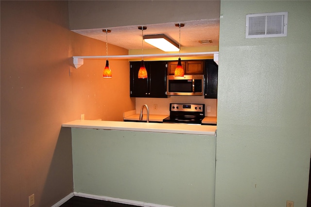 kitchen featuring decorative light fixtures, kitchen peninsula, appliances with stainless steel finishes, and sink