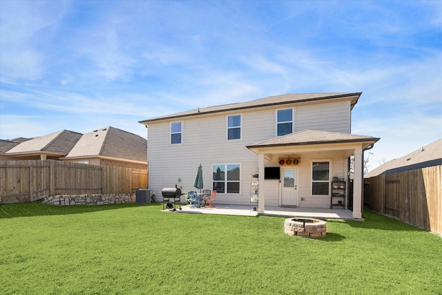 back of property with central AC unit, an outdoor fire pit, a patio area, and a yard