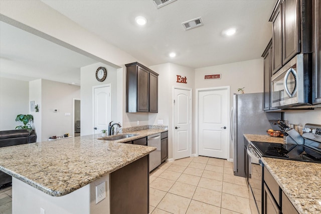 kitchen with appliances with stainless steel finishes, light stone countertops, light tile patterned floors, dark brown cabinetry, and sink