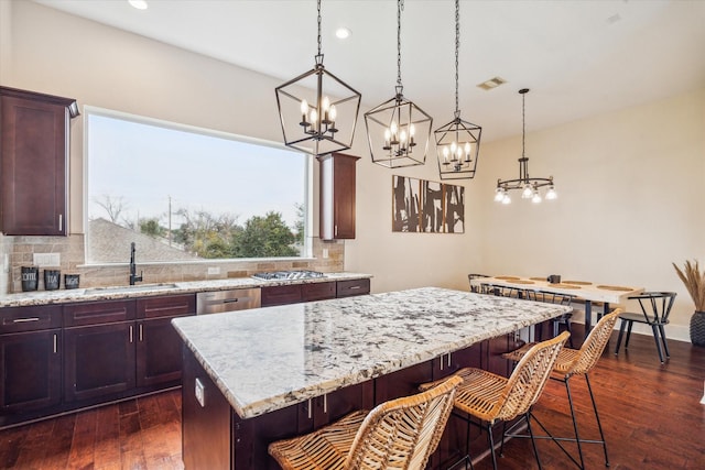 kitchen featuring hanging light fixtures, dark hardwood / wood-style floors, a kitchen island, sink, and backsplash