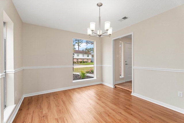 spare room with a chandelier and hardwood / wood-style flooring