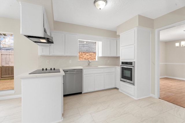 kitchen featuring stainless steel appliances, a notable chandelier, white cabinetry, and sink