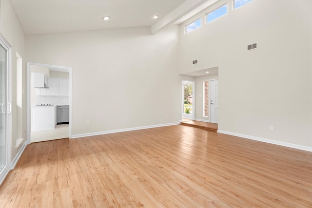 unfurnished living room featuring a high ceiling and light hardwood / wood-style flooring