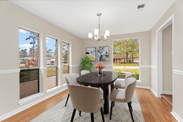 dining space with light wood-type flooring and a notable chandelier