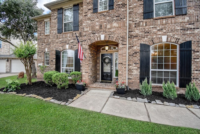 view of exterior entry featuring a garage and a lawn