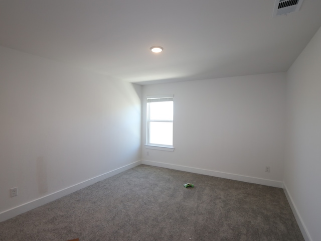 unfurnished room featuring carpet, visible vents, and baseboards