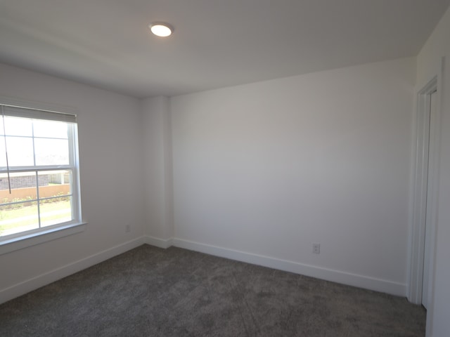 empty room with dark colored carpet and baseboards