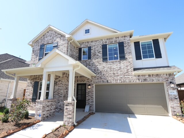 view of front of home with an attached garage, covered porch, driveway, and brick siding
