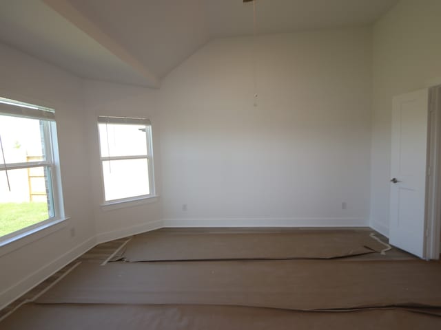 empty room featuring vaulted ceiling and baseboards