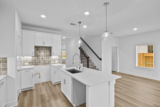 21734 Persian Lake Dr, Cypress, TX 77433 - kitchen featuring a sink, light wood-style flooring, backsplash, white cabinetry, and decorative light fixtures
