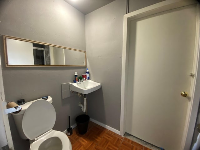 bathroom featuring sink, parquet floors, and toilet