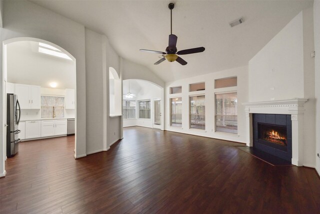 unfurnished living room featuring ceiling fan, dark wood-type flooring, vaulted ceiling, and a fireplace