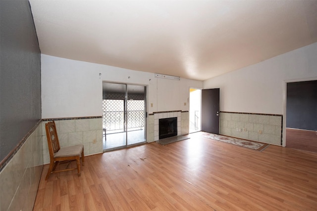 unfurnished living room with a tiled fireplace and light hardwood / wood-style floors