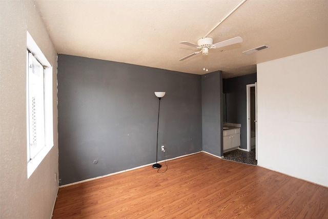 unfurnished bedroom with a textured ceiling, ceiling fan, and dark wood-type flooring