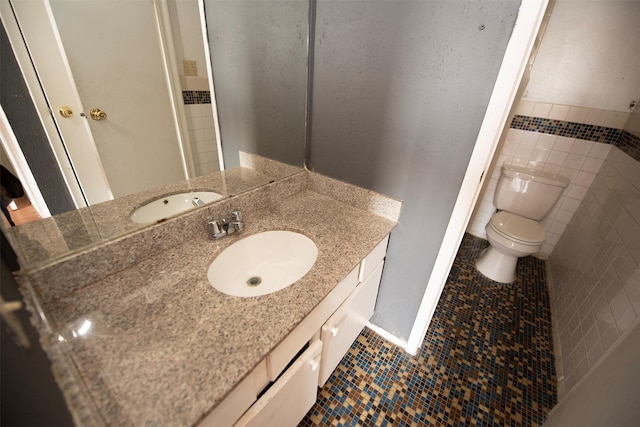 bathroom with toilet, tile patterned flooring, tile walls, and vanity