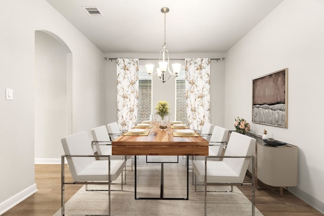 dining space featuring hardwood / wood-style flooring and a notable chandelier