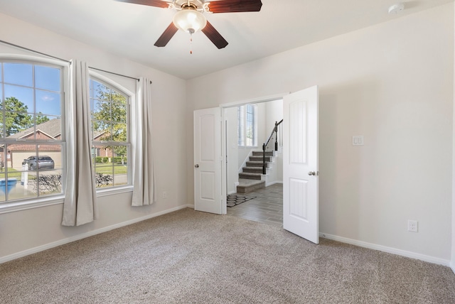 empty room featuring ceiling fan and light carpet