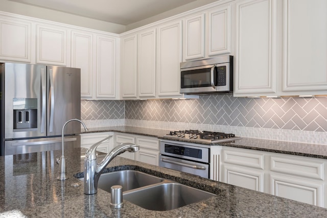 kitchen featuring stainless steel appliances, dark stone countertops, and white cabinetry