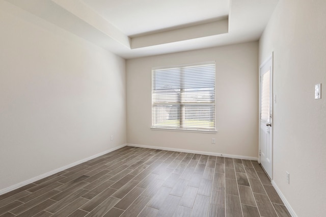 spare room with dark hardwood / wood-style flooring and a raised ceiling