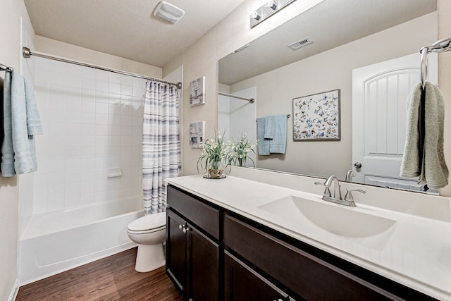 full bathroom featuring hardwood / wood-style floors, toilet, vanity, a textured ceiling, and shower / tub combo with curtain