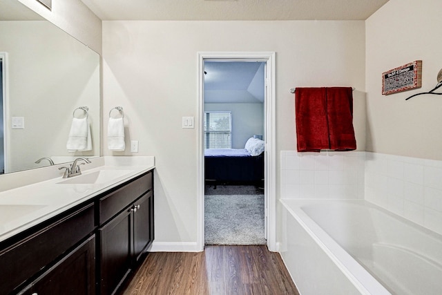 bathroom with hardwood / wood-style flooring, a tub to relax in, and vanity