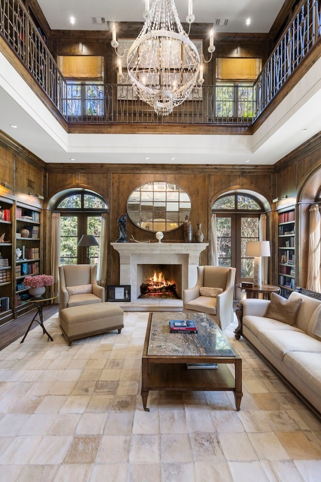 interior space with french doors, a chandelier, a towering ceiling, and wood walls