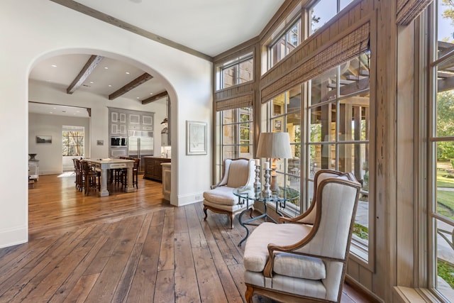 living area with beamed ceiling, hardwood / wood-style floors, and plenty of natural light