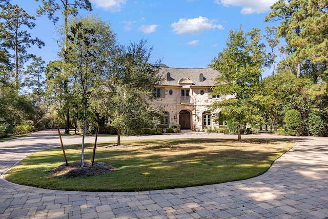 french country home with a front yard and a balcony