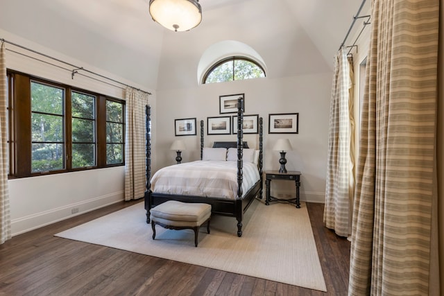 bedroom with high vaulted ceiling and dark wood-type flooring