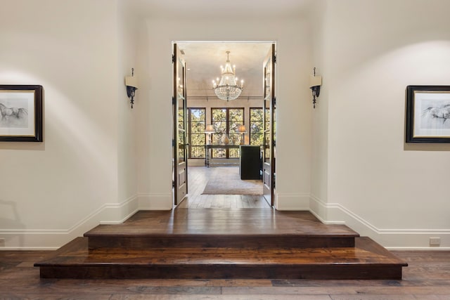 entrance foyer with french doors, an inviting chandelier, and hardwood / wood-style flooring