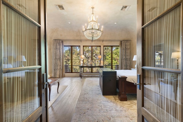 interior space featuring a towering ceiling, french doors, an inviting chandelier, and hardwood / wood-style floors