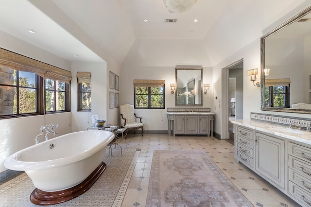 bathroom with lofted ceiling, a bath, a wealth of natural light, and vanity