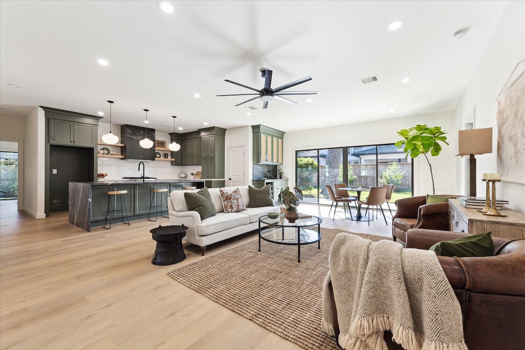 living room featuring ceiling fan, light hardwood / wood-style floors, and sink