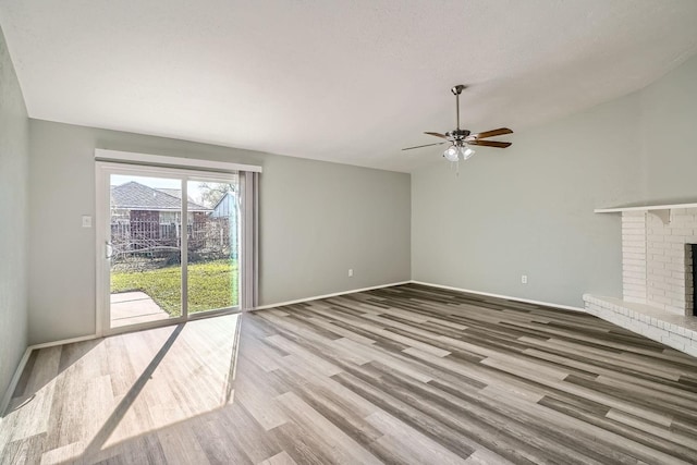 unfurnished living room featuring ceiling fan, a brick fireplace, a textured ceiling, and wood-type flooring