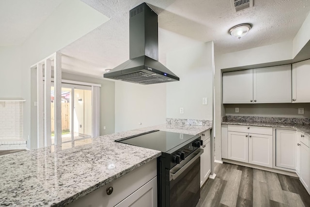 kitchen with island range hood, black range with electric stovetop, light stone countertops, a textured ceiling, and white cabinets