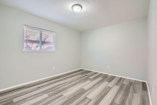 unfurnished room with a textured ceiling and light wood-type flooring